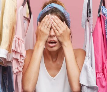 Young attractive woman covering eyes with hands, expecting surprise from her boyfriend who bought her new dress. Beautiful female model anticipaiting for something while standing in cloakroom
